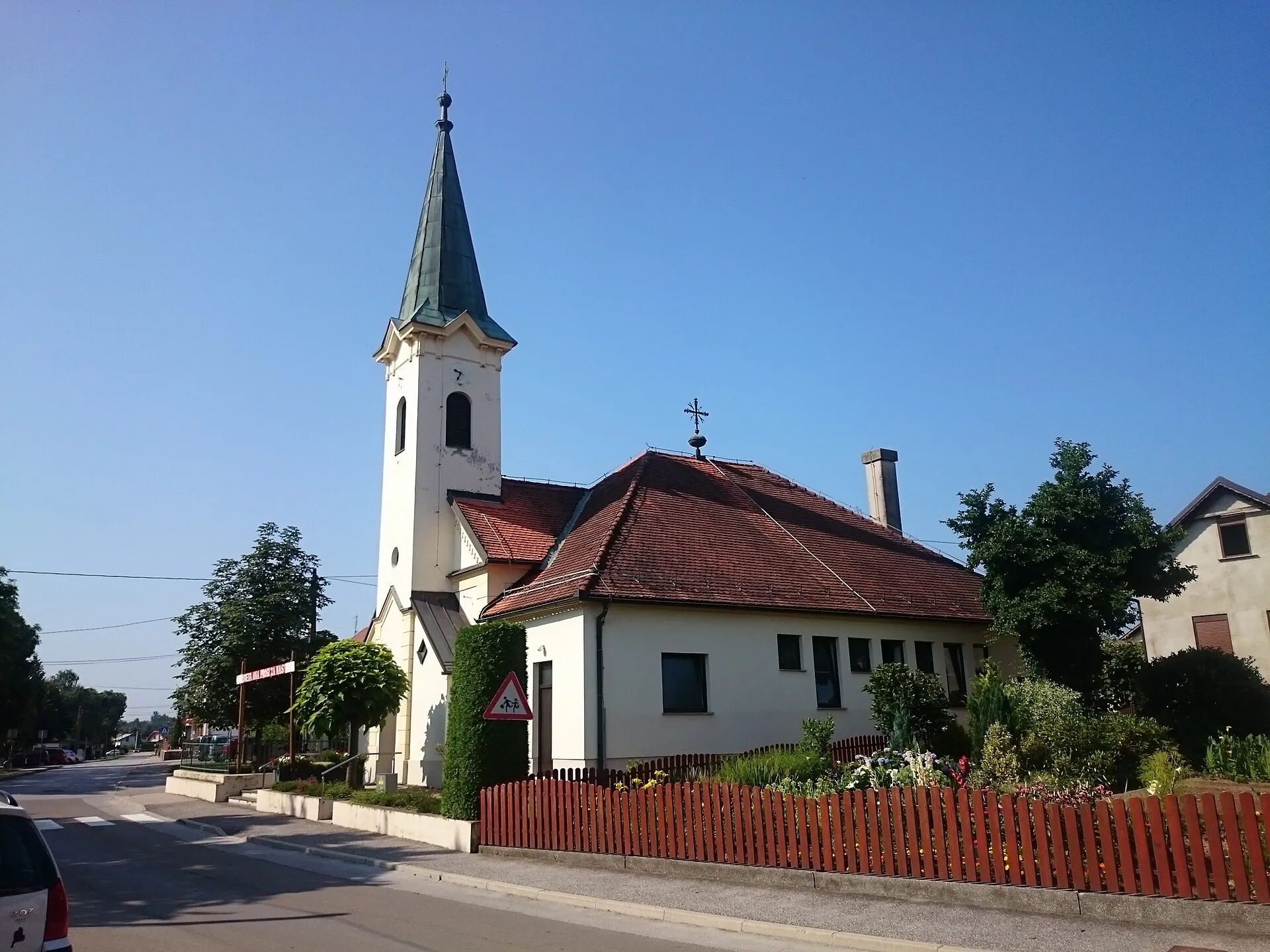 Župnijska cerkev sv. Ane v Bakovcih s koničastim zvonikom in župniščem