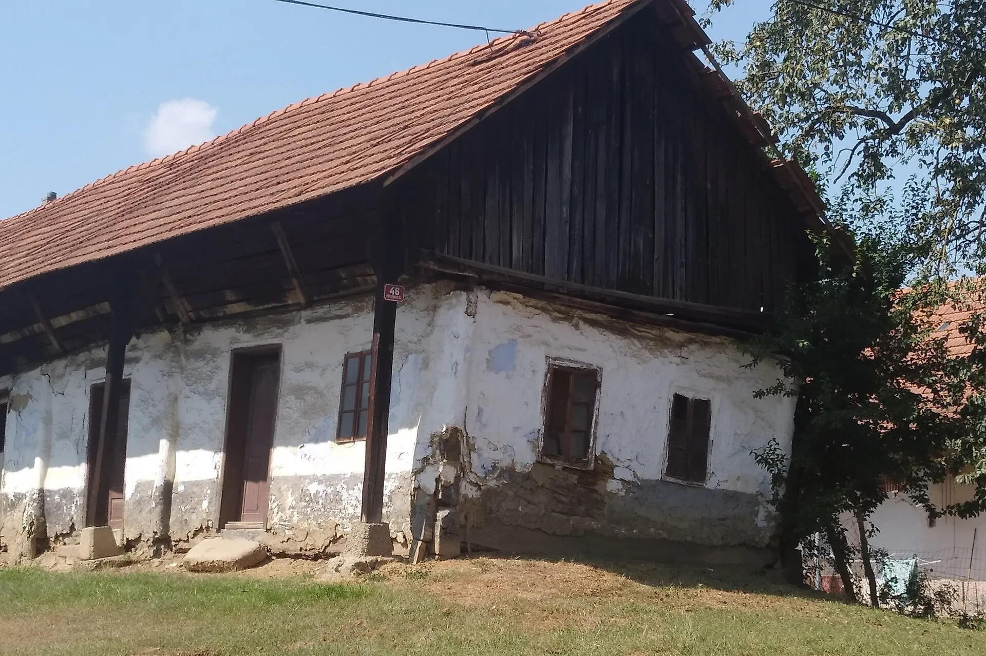 Stara kmečka hiša z ilovnatimi stenami in lesenim zatrepom v Bakovcih